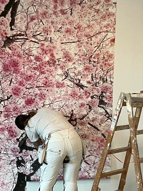 Maler ved væg med kirsebærblomster og en stige på plejehjemmet Rosenlunden