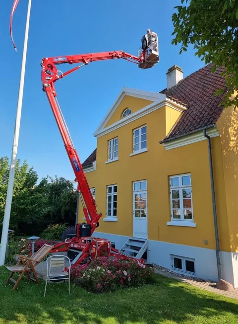Gul bygning med hvide vinduer og rød lift ved taget